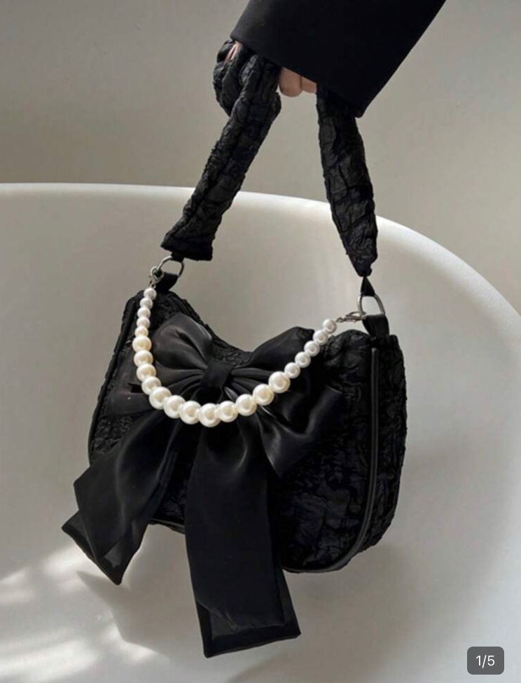 Bolsa negra de mano, con decoración de moño y cadena de perlas